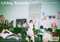 Eine Gruppe singt und tanzt in einem gemütlichen, schwach beleuchteten Raum, der mit Postern und Kunstwerken dekoriert ist. Einige Teilnehmer sitzen, andere stehen und heben die Arme, wodurch eine lebhafte und energiegeladene Karaoke-Atmosphäre entsteht.